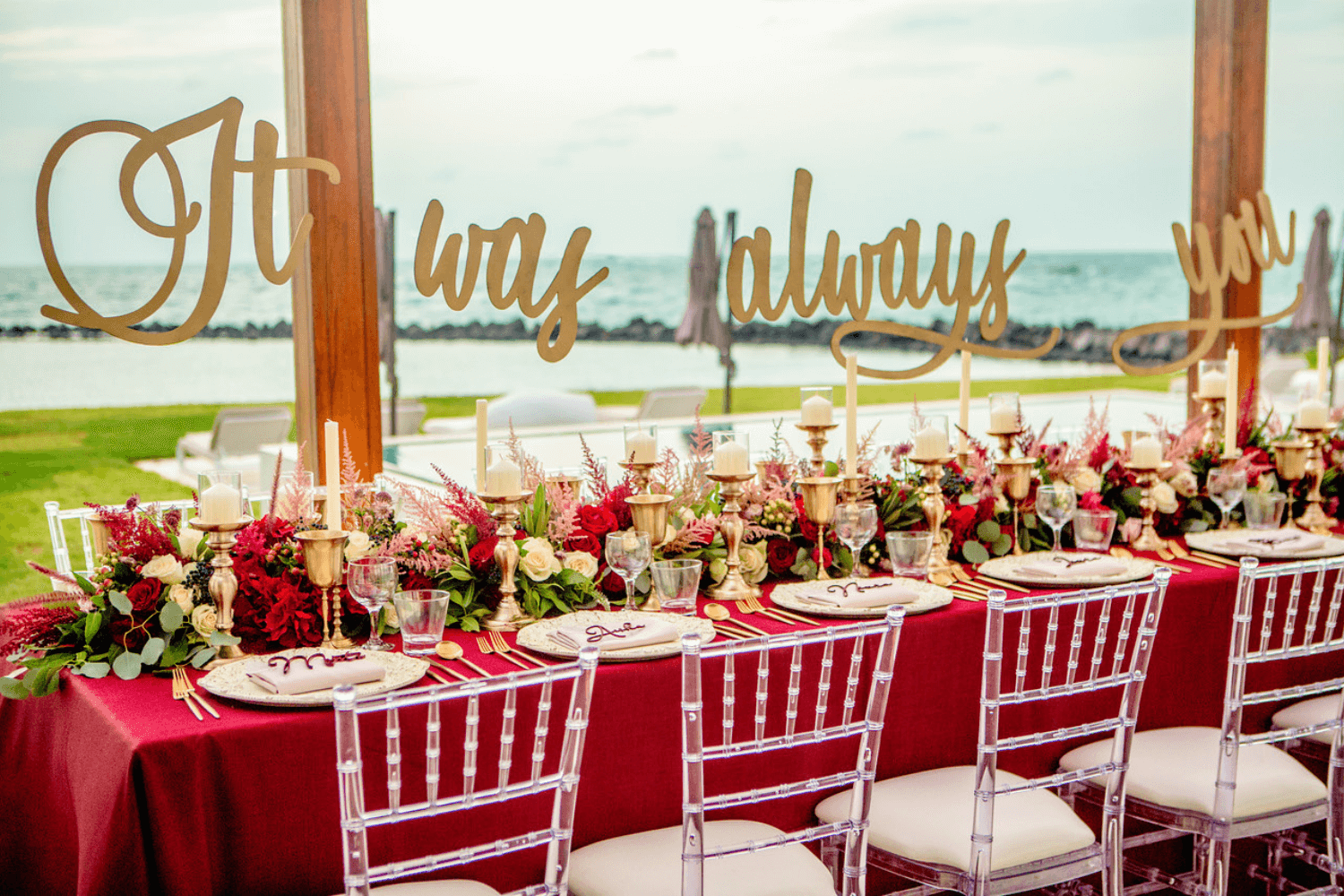 Elegant bridal shower setup with soft pastel linens, candlelit tables, and floral centerpieces on a beachside venue at sunset.