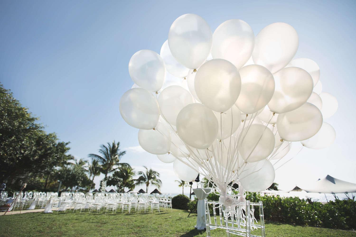 A large collection of white balloons in a field, perfect for parties and special occasions.