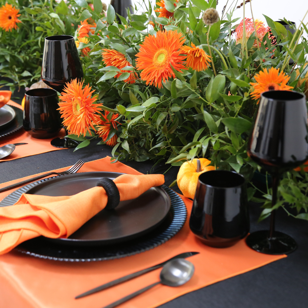 Pumpkins & Petals- Dining Setup for 8, featuring black and orange tableware, acrylic chairs, and a vibrant floral centerpiece with decorative pumpkins.