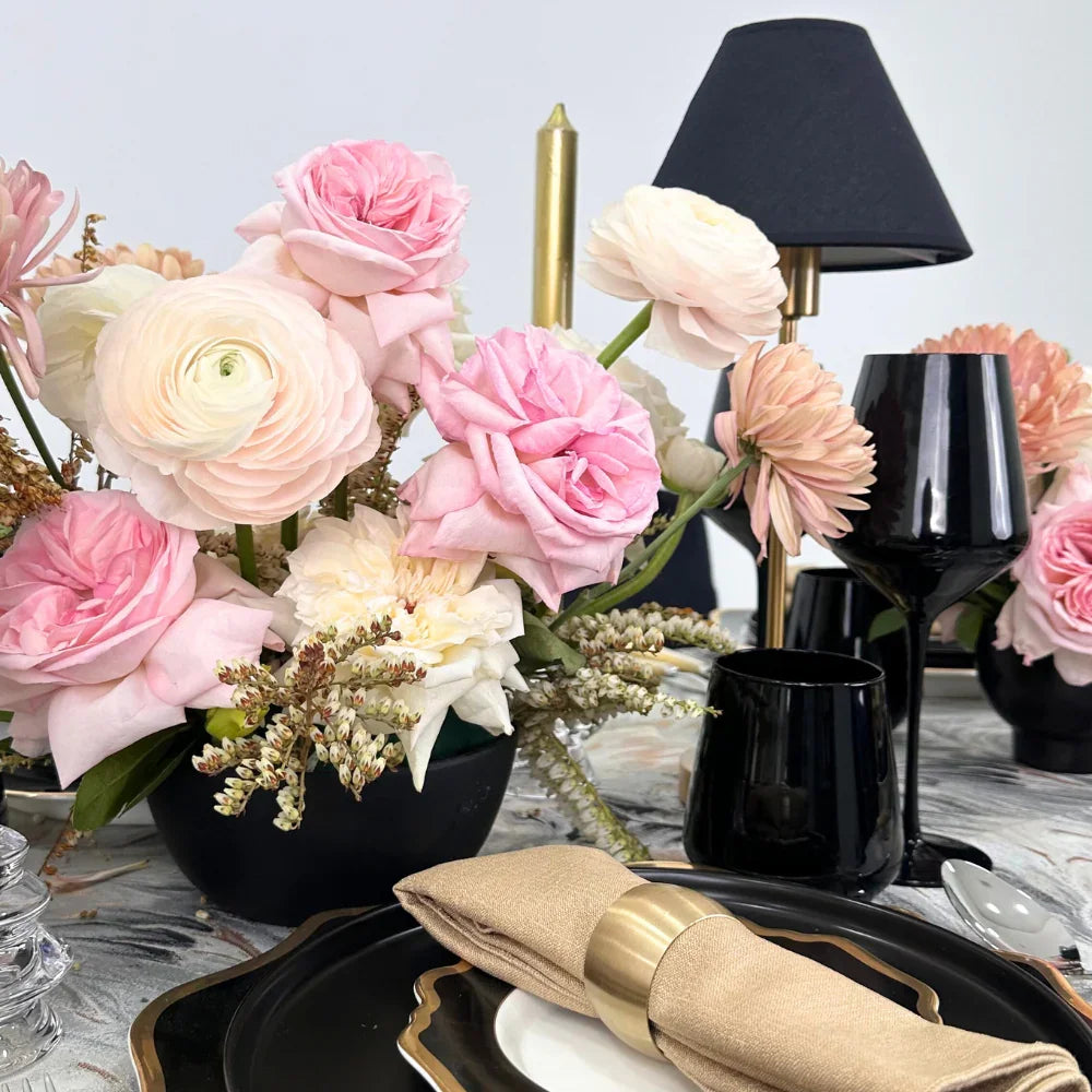 Opulent Twilight-Dining Setup featuring a table set for eight with elegant plates, black chairs, glassware, and floral centerpieces, ideal for sophisticated events.