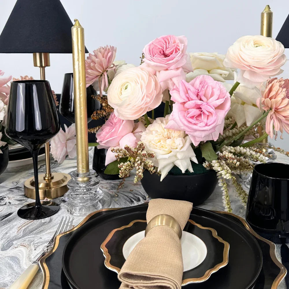 Opulent Twilight-Dining Setup featuring a table for eight with black and gold tableware, pink floral centerpieces, wine glasses, and elegant cutlery.