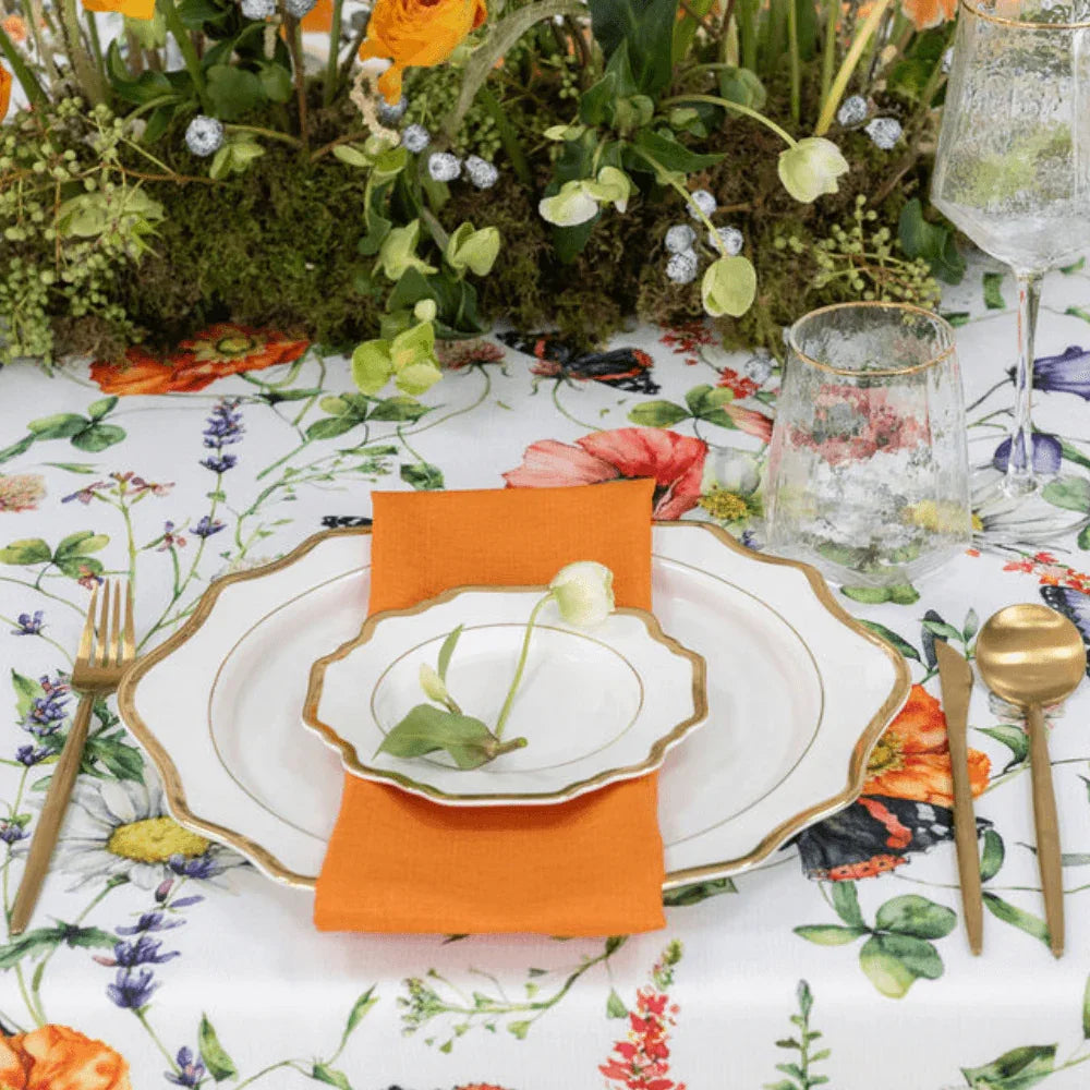 Butterfly Meadows- Dining Setup: Elegant table arrangement for eight, featuring plates, gold cutlery, glasses, and a floral centerpiece, ideal for special events.