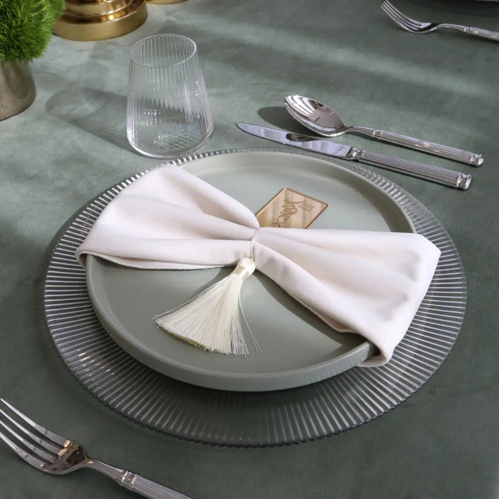 CHARGER PLATE - LINED enhances this elegant table setting with polished silverware, a bow-tied napkin, and a fluted tumbler, perfect for stylish dining events.