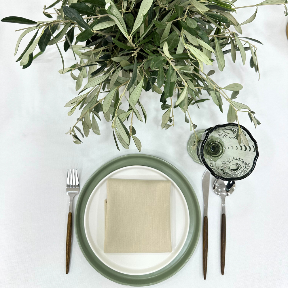 Sage ceramic plates on a table setting with silverware and a plant, ideal for elegant events by Party Social.