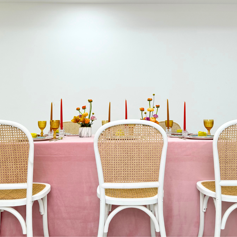 Blush Velvet Dreams-Dining Setup featuring a table with candles, flowers, and eight rattan chairs, perfect for hosting elegant dinner parties or special events.