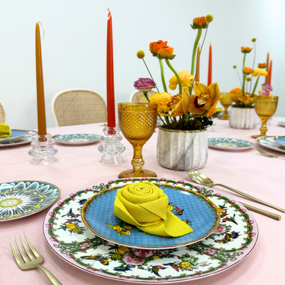 Blush Velvet Dreams-Dining Setup featuring a table set for eight with plates, napkins folded into roses, cutlery, goblets, and floral centerpieces.
