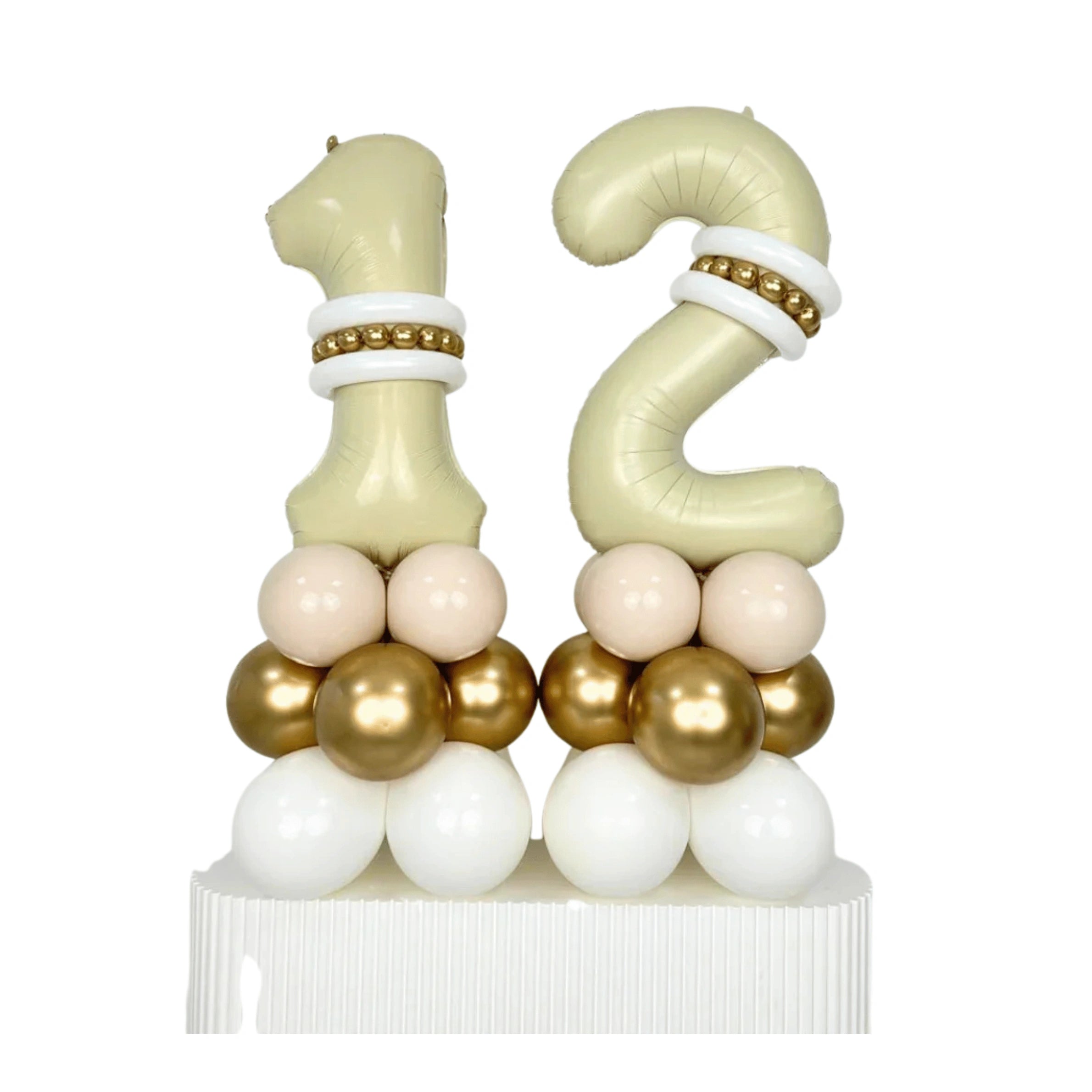 A 12th birthday balloon decoration set featuring a large number 1 foil balloon and a number 2 foil balloon, both in a pale champagne color with white and gold bands, supported by clusters of white, blush pink, and metallic gold balloons on a white base.