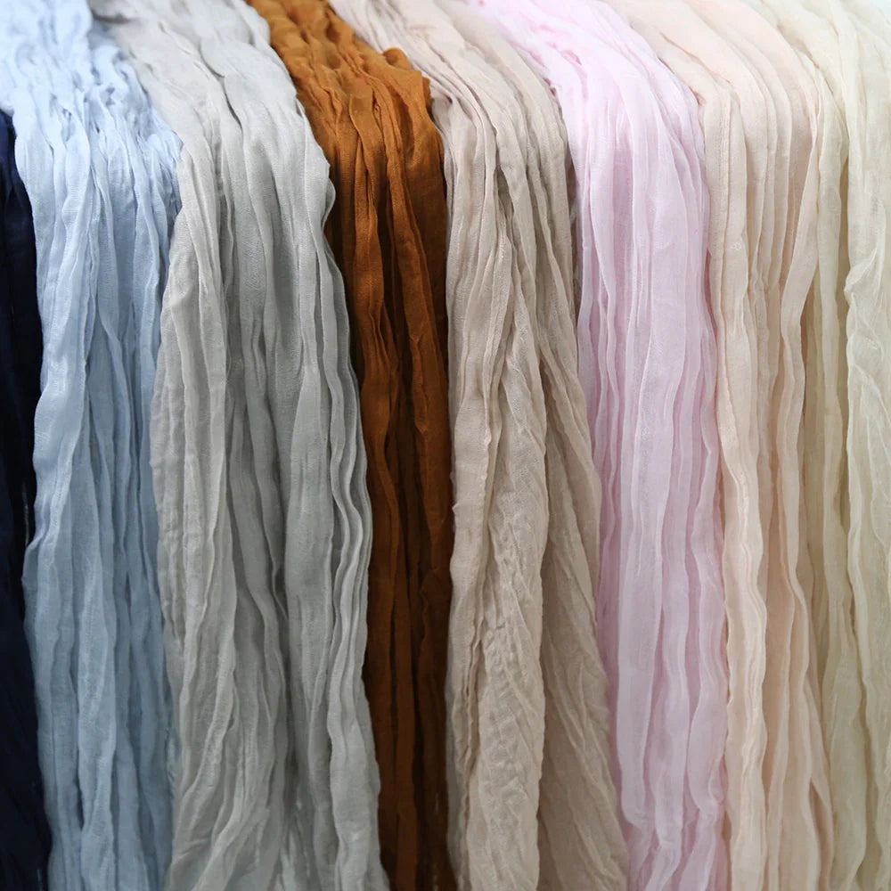 Gauze table runners displayed on a rack, showcasing their premium creased effect, ideal for enhancing elegant tabletops at special events and occasions.
