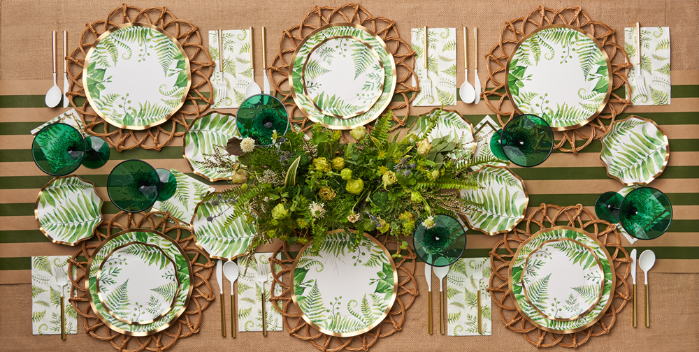 Fern &amp; Foliage Paper Dinner Plate-8 Per Package from Party Social: Elegant paper plates with green ferns, gold foil trim. Set with green and white plates, silverware, and a green bell on a table.