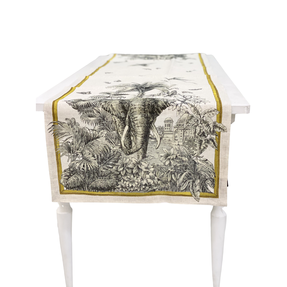 Tantra Pure Linen Runner featuring an elephant in lush foliage, with architectural motifs and an ochre border, enhancing any dinner or event table setting.
