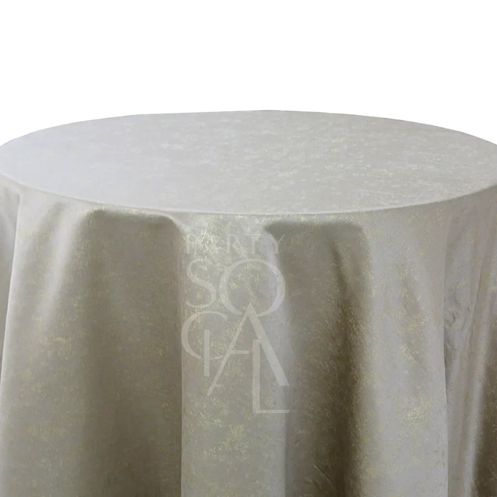 GREY IN SHIMMERING GOLD ROUND TABLE CLOTH: A round champagne-beige tablecloth with a shimmery texture, featuring a central “PARTY SCALE” watermark. Ideal for elegant event settings.
