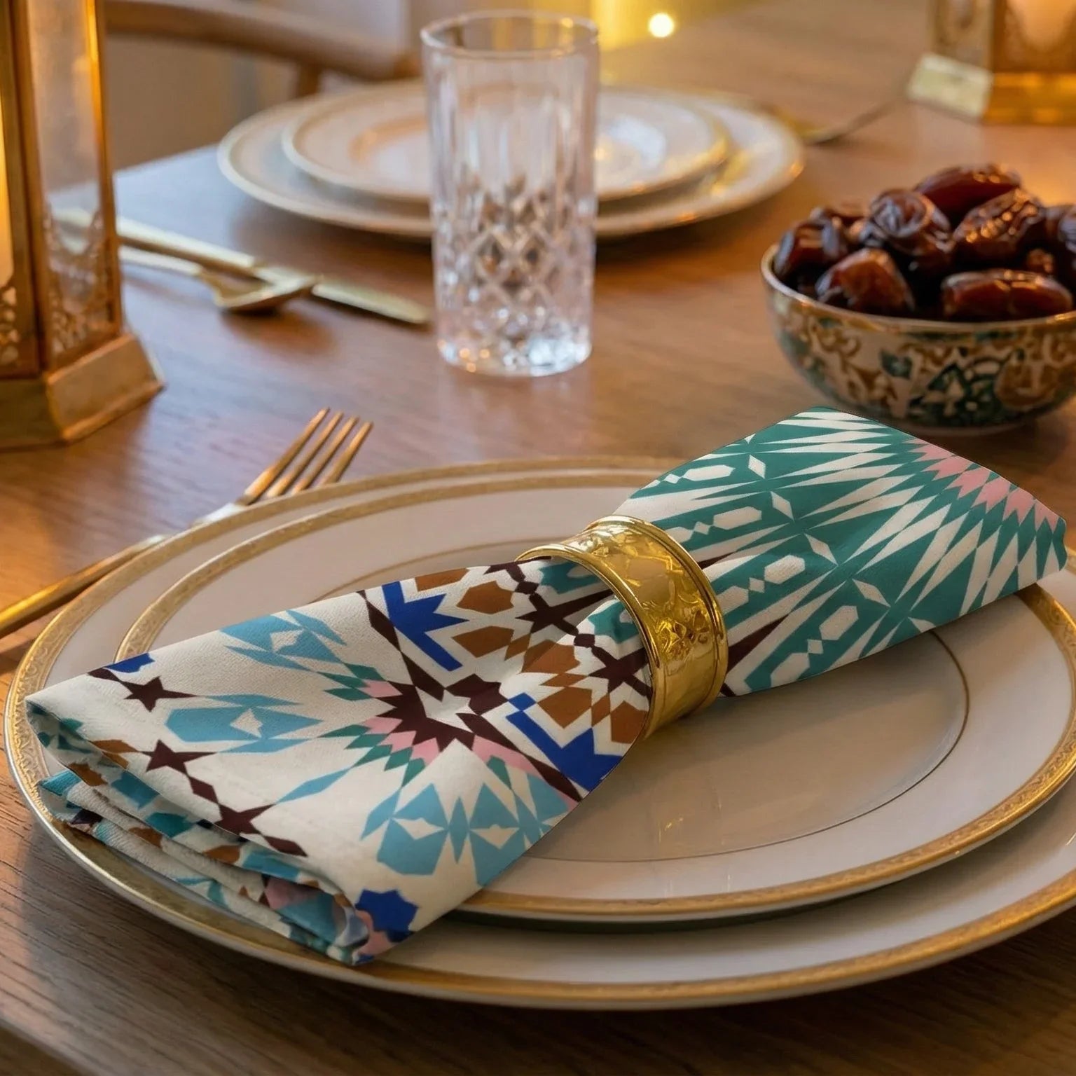 Arabesque Gift Box set includes gold-rimmed plates, geometric napkins with gold rings, and crystal glass, creating an elegant and inviting Ramadan tablescape.