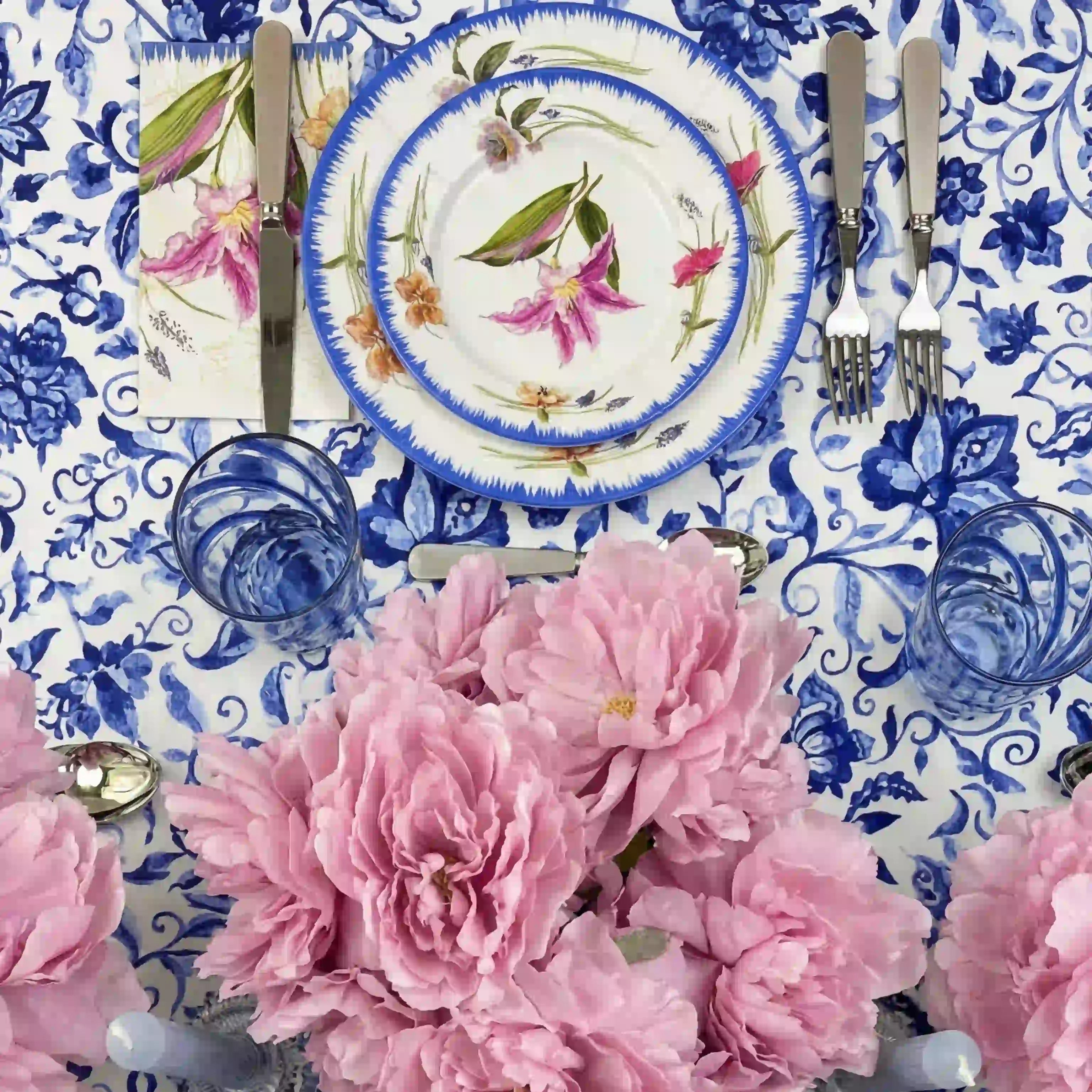 Azure Garden Floral Tablecloth with vibrant floral pattern, set beneath elegant china, peonies, and silver candleholders in a sophisticated spring table setting.