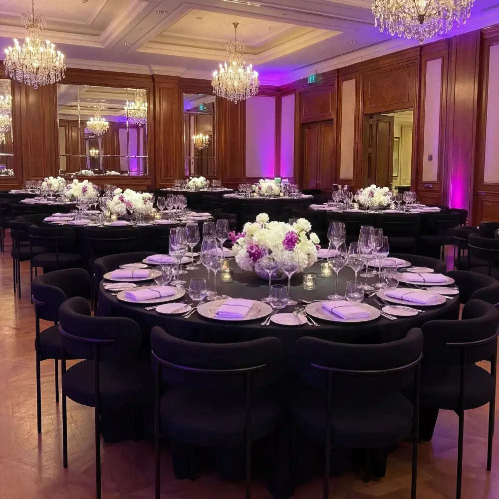 Bouclé Dining Chairs encircle banquet tables, enhancing the formal setup with their modern, textured design amidst elegant floral arrangements and crystal chandeliers.