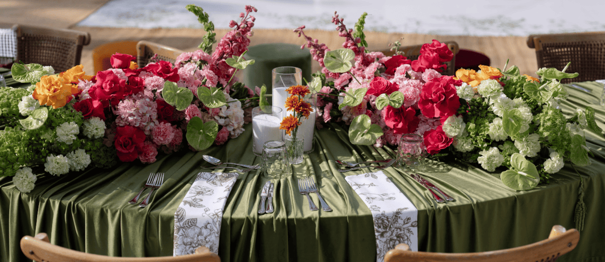 Green velvet decorative table setting with floral arrangements and green tablecloth.