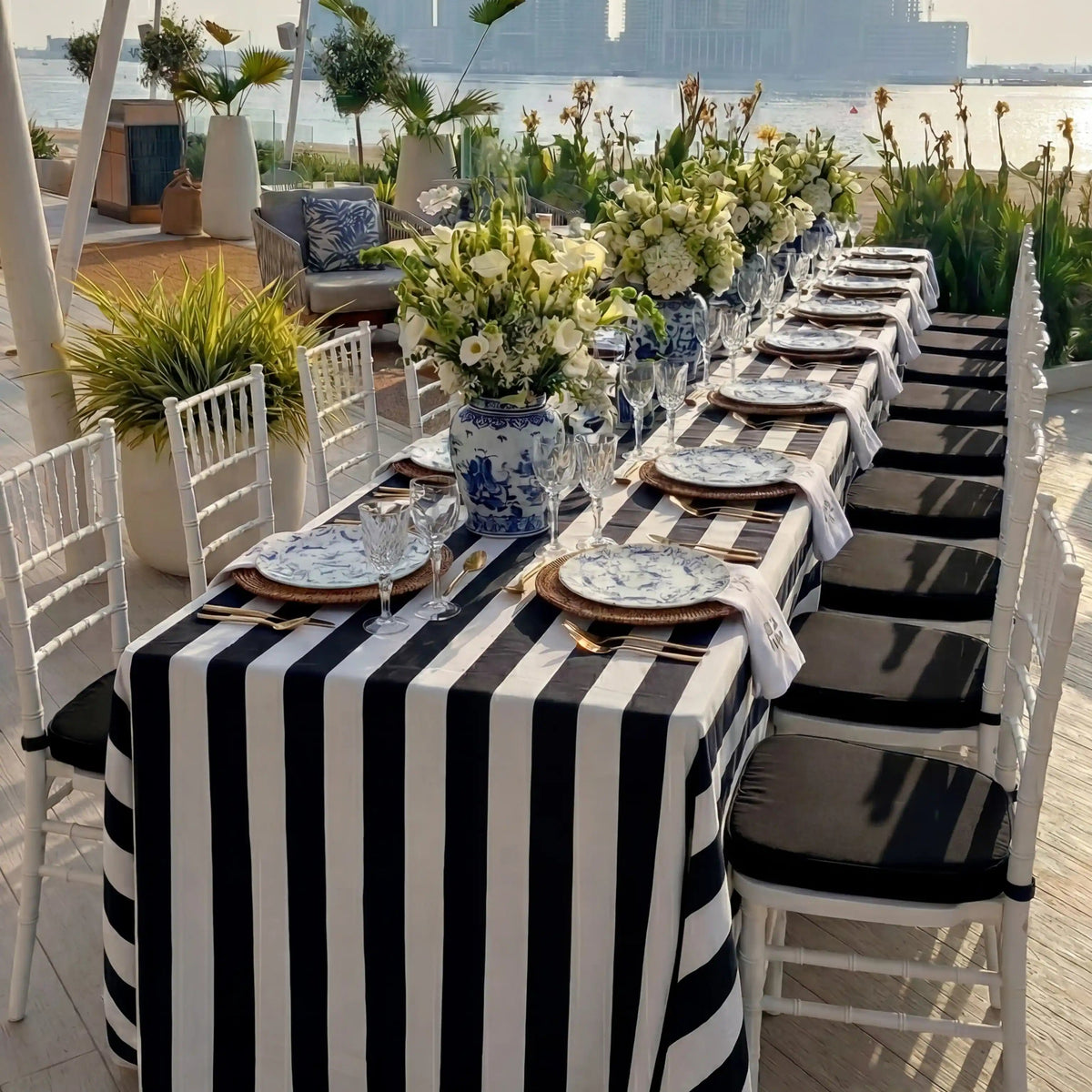 Monochrome Linen Tablecloth on waterfront dining setup with striped design, paired with elegant tableware and floral decor, perfect for sophisticated events.