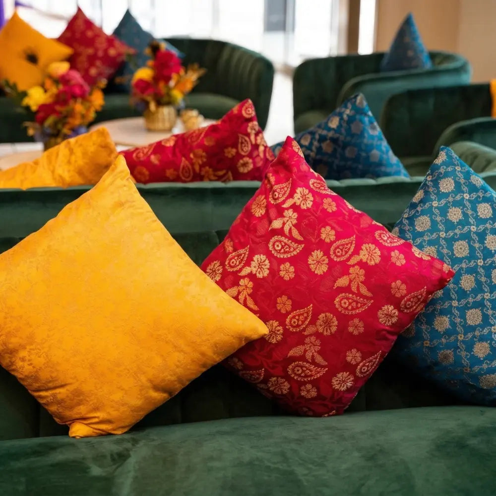 CUSHION COVER BROCADE on plush green velvet seating with vibrant pillows, showcasing premium brocade fabric, perfect for enhancing party or event decor.