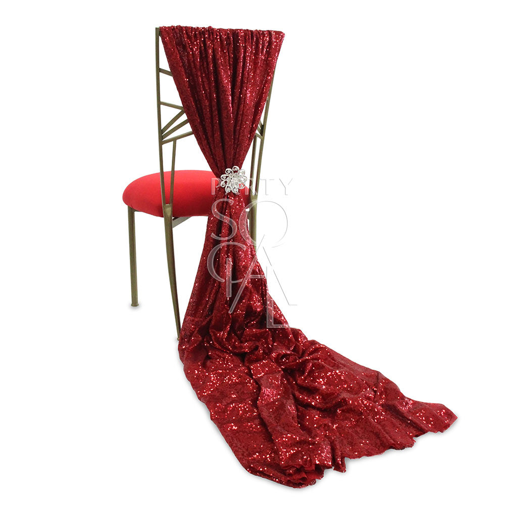 CHAIR COVER RED SEQUIN TRAIN CHAMELEON on a Chameleon chair, featuring a dramatic red sequin design with a brooch accent, ideal for elegant events.