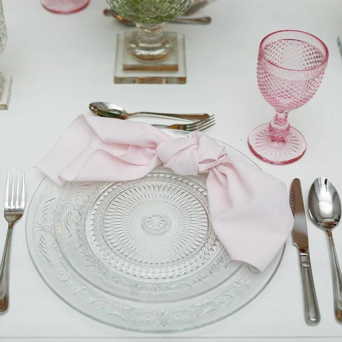 Vintage clear glass plates with pink napkin; features fork and spoon setup. Ideal for elegant table settings.