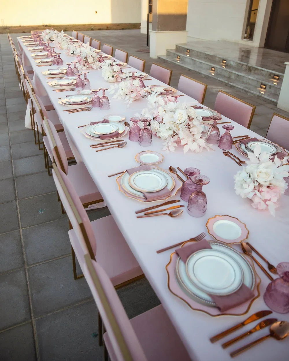 CHARLOTTE CANTILEVER VELVET CHAIR elegantly set at a long dining table with plates and flowers, ideal for weddings and events.