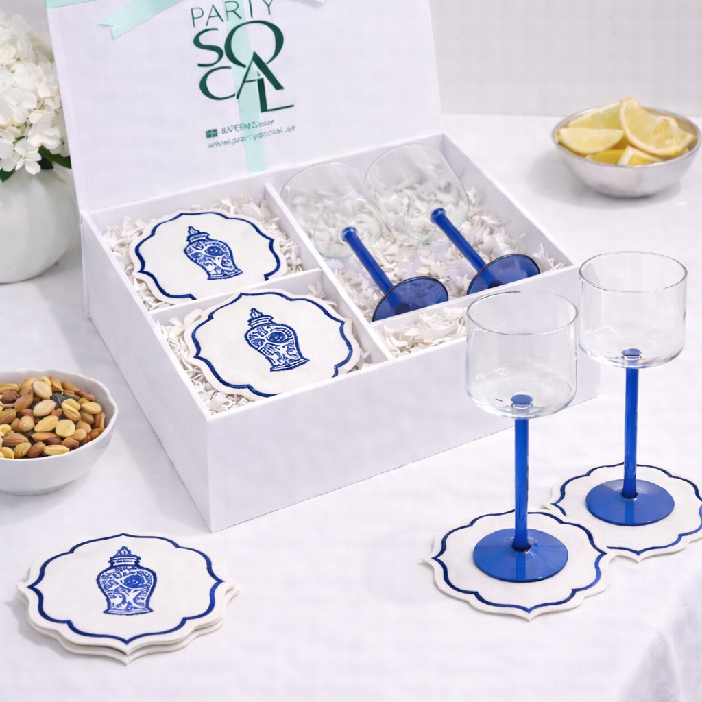 White gift box with blue-stemmed glasses and scalloped-edge coasters, featuring a ginger-jar motif, set for elegant home entertaining and Ramadan gifting.