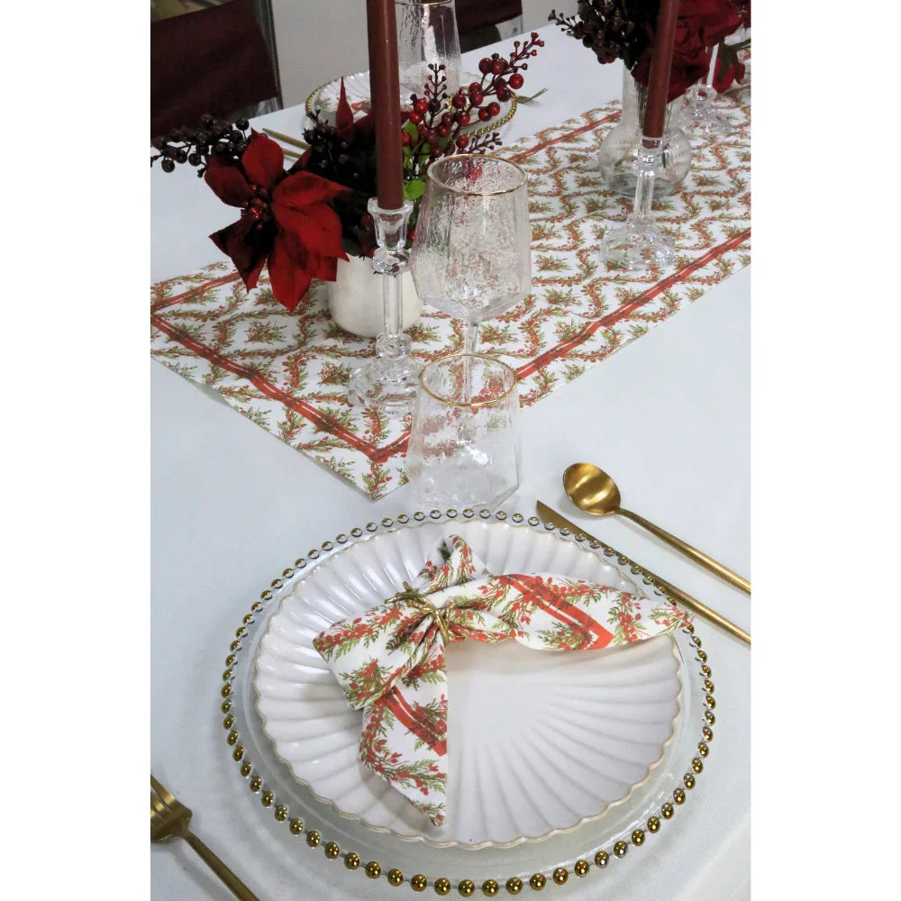 Holly & Pine Linen Runner elegantly enhances a festive table with matching napkins, gold-trim chargers, and flatware, perfect for a luxurious Christmas setting.