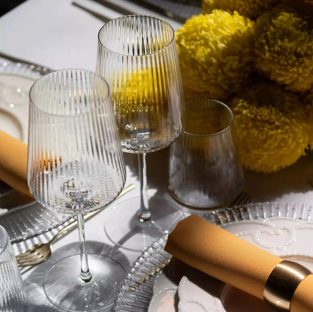 Clear Lined Glassware Collection featured in an elegant table setting with crystal wine glasses, a ridged tumbler, and a mustard-gold napkin, embodying refined event aesthetics.