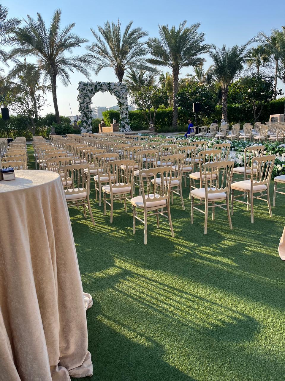 NAPOLEON CREAMWASH CHAIR set on a grassy field, ideal for weddings or corporate events, showcasing its rustic, elegant design suitable for various occasions.