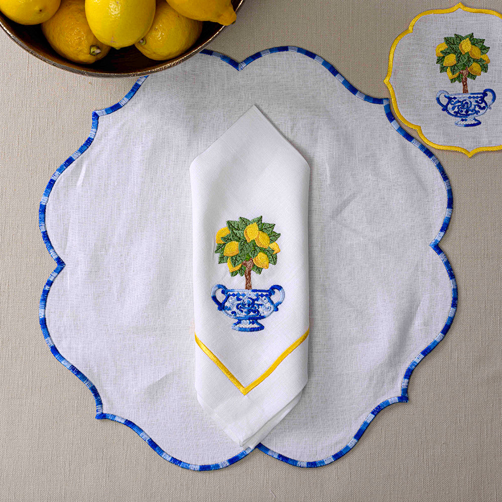 Lotus Pure Linen Placemat - 2 per pack: White napkin with embroidered design, lemons in bowl, and lemon tree on towel.