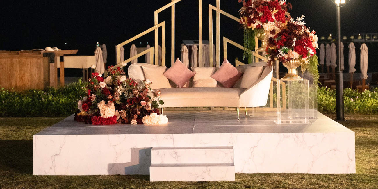 Decorative setup with flowers and pillows on a platform at night