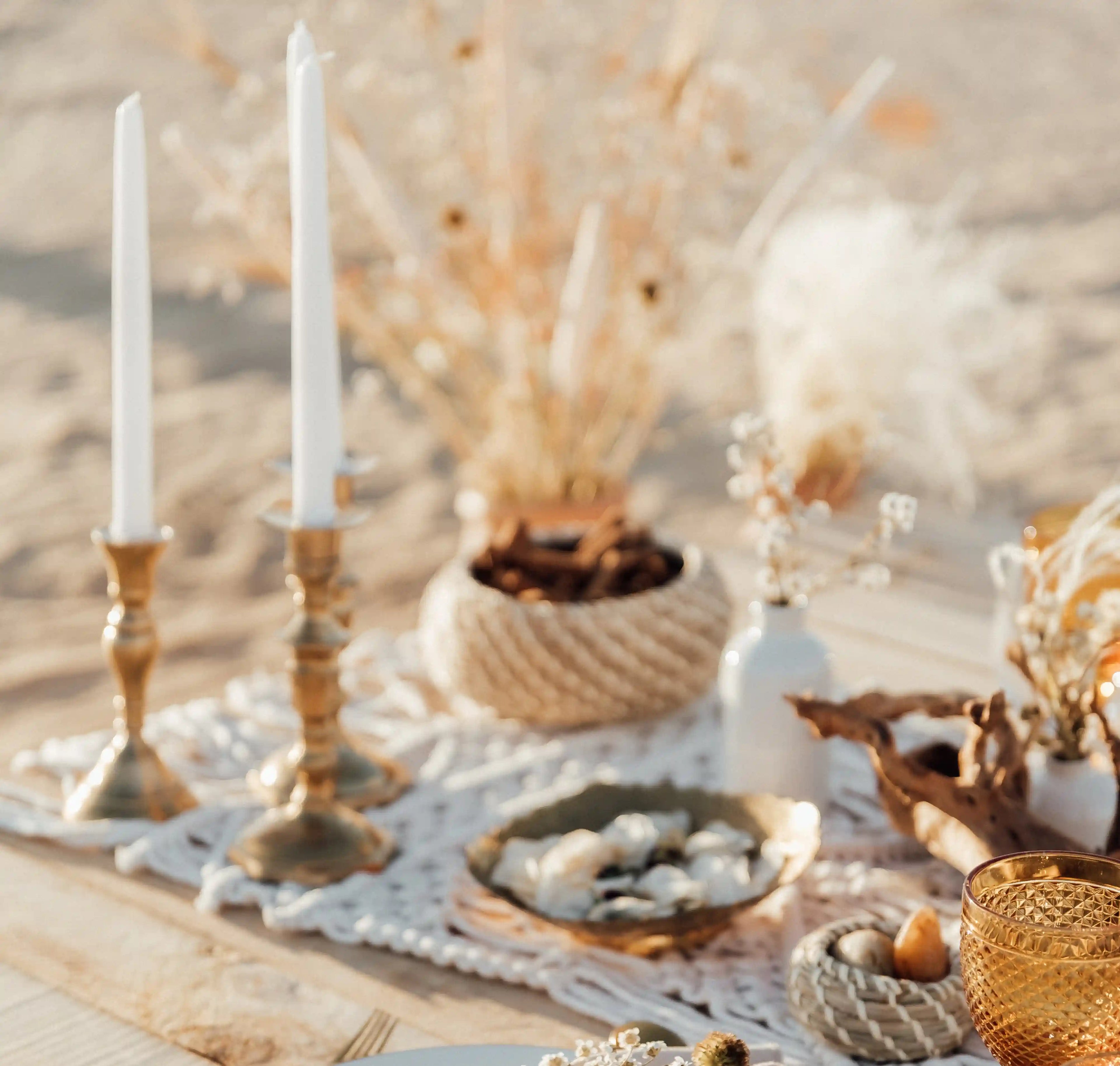 Brass candlesticks set of 3 on a boho tablescape with candles, enhancing a rustic event vibe with dried botanicals and seashells.