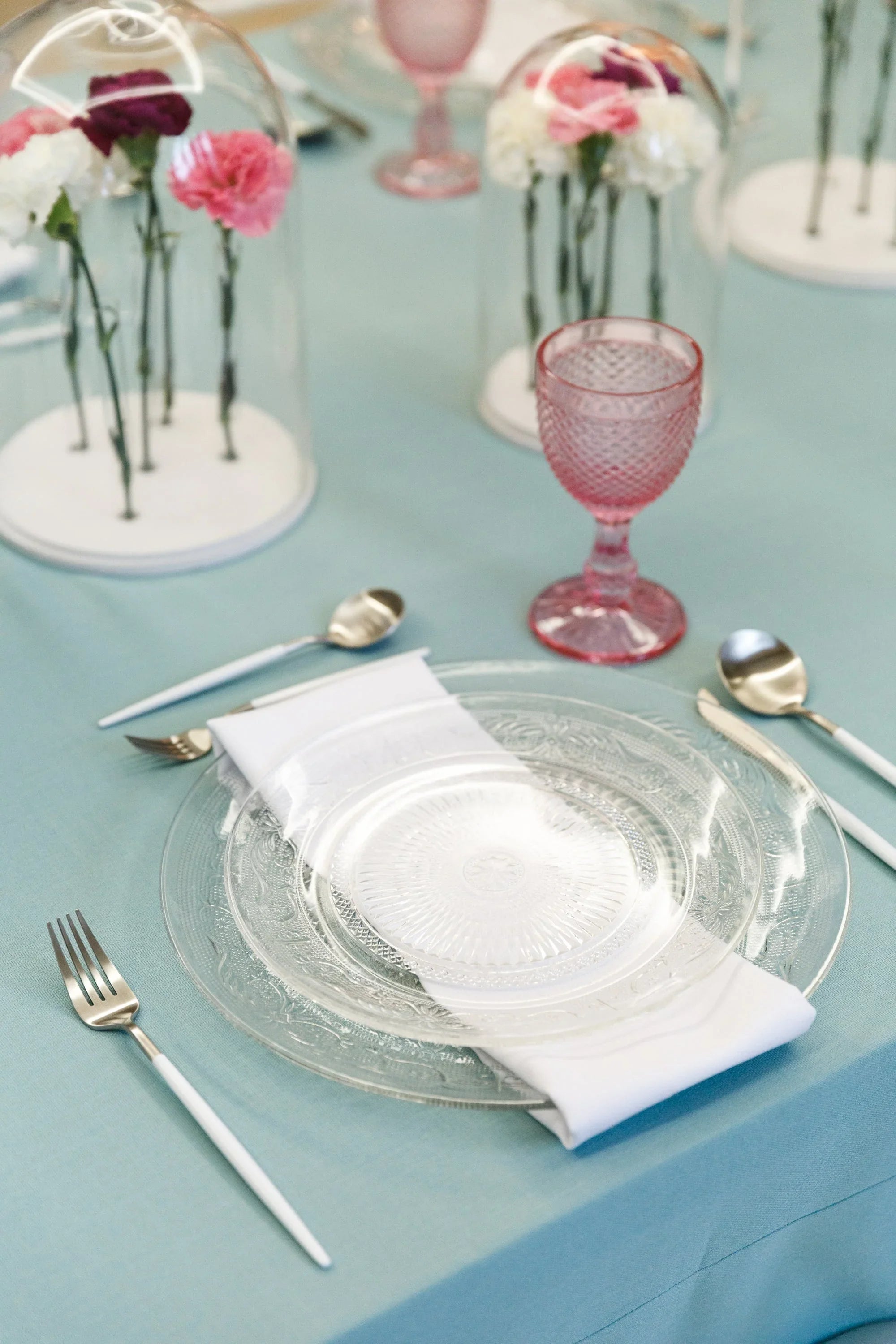 Vintage clear glass plates, delicately etched, displayed on a table with matching glassware and utensils, ideal for elegant table settings at events or special occasions.