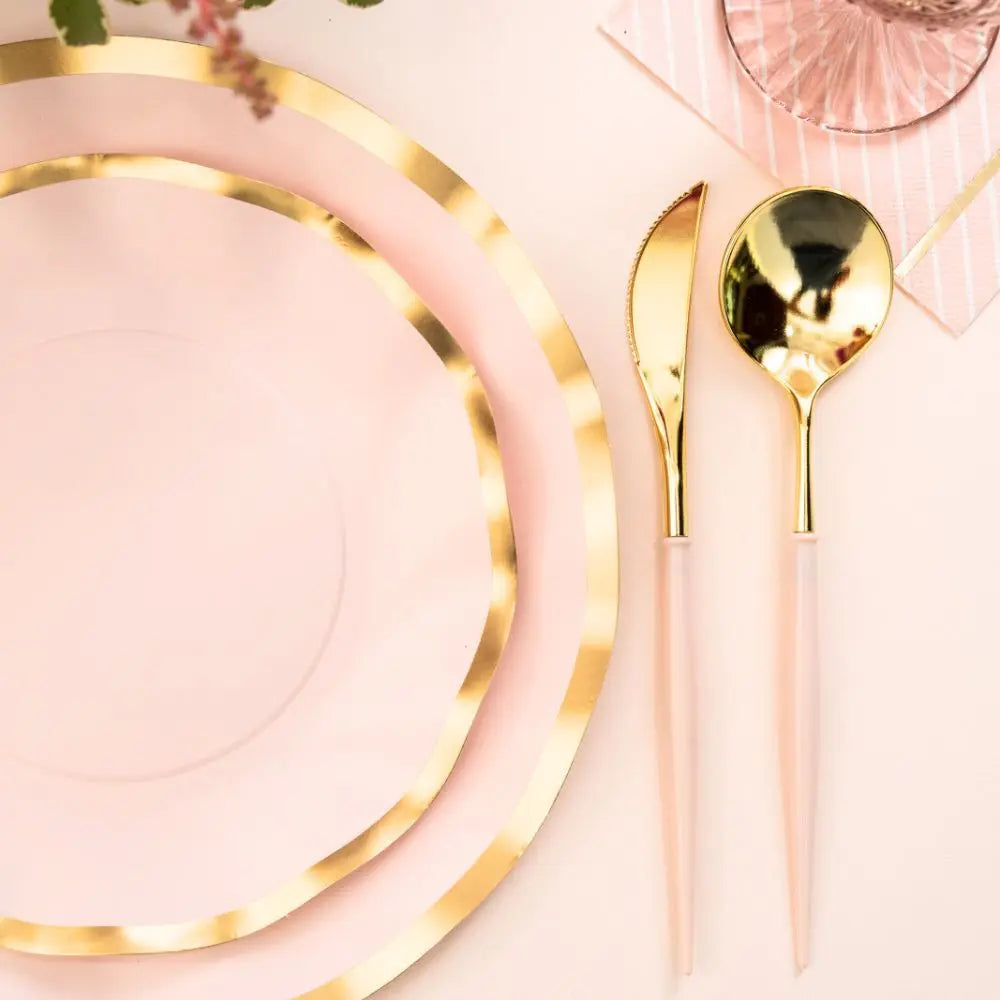 Pink plates with gold rims and matching cutlery on a pink background