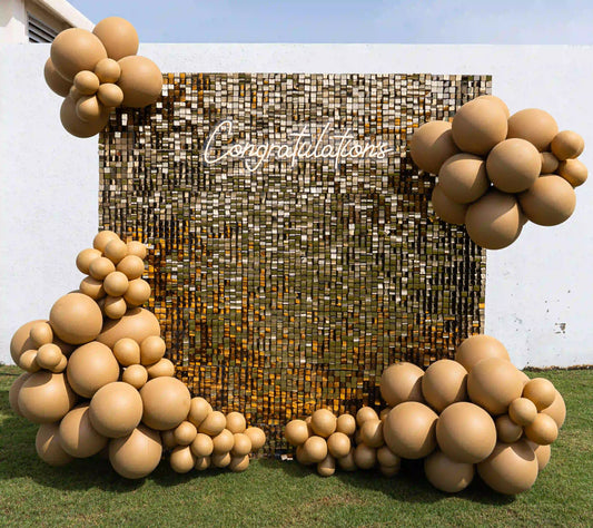 Golden Shimmer Celebration Wall featuring reflective gold tiles and warm beige balloons, perfect for elegant event photo backdrops. Ideal for special celebrations.