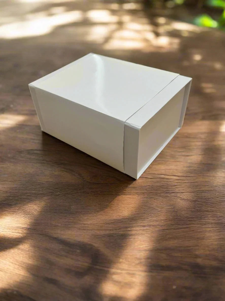 White Gift Box on a wooden table, showcasing a premium design with a magnetic fold-over lid, ideal for presenting elegant gifts.