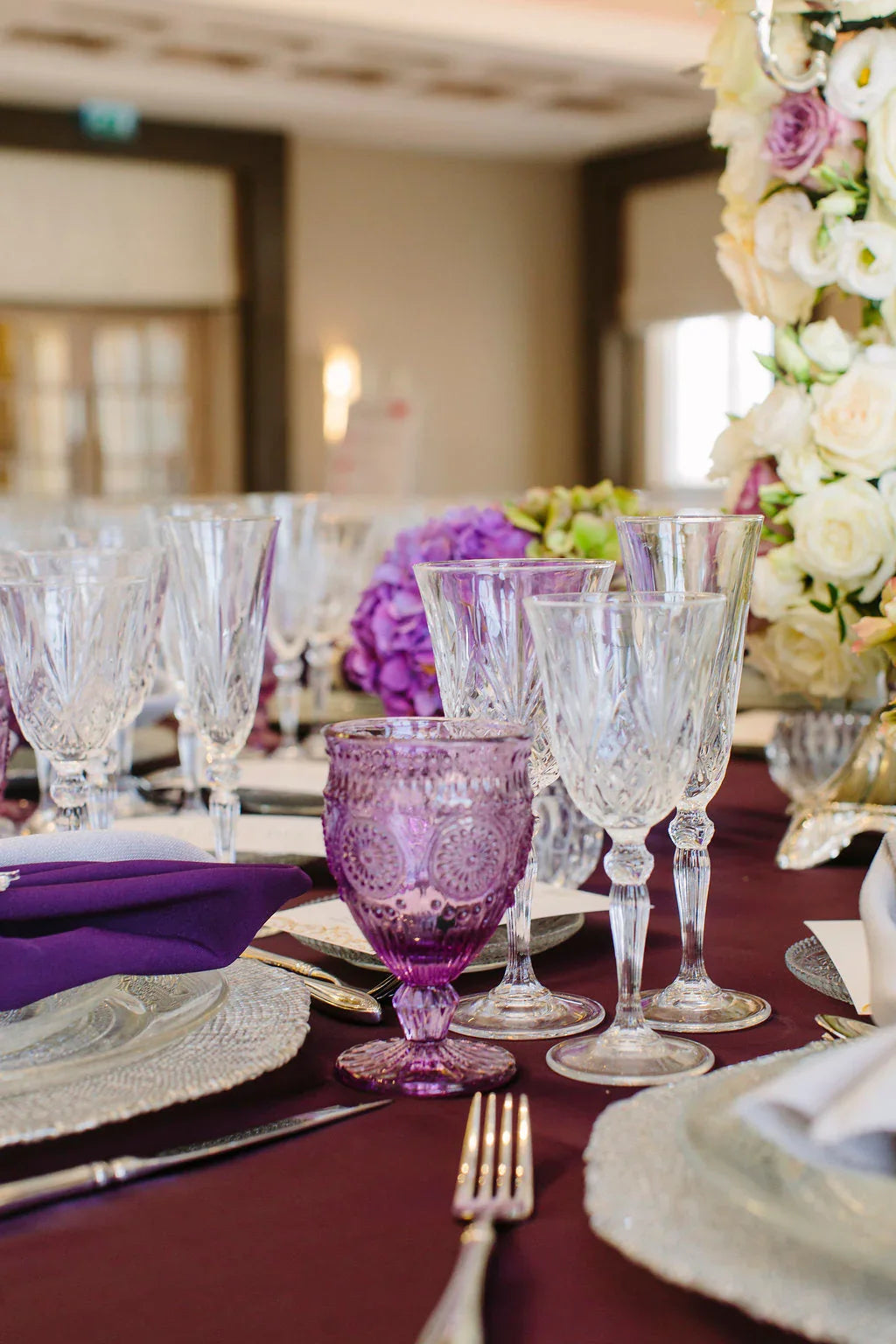 Crystal Rome glasses elegantly arranged on a table, surrounded by wine glasses and a floral centerpiece, perfect for enhancing any premium event or dinner party.