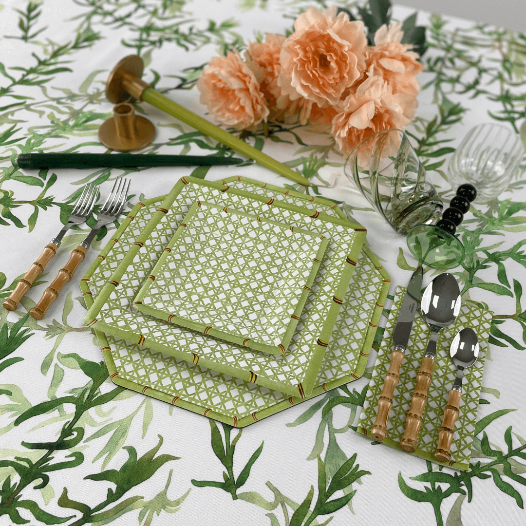 Holly Trellis Square Paper Salad & Dessert Plates on a table with floral tablecloth, spoon, fork, knife, and glasses; ideal for elegant, effortless dining.