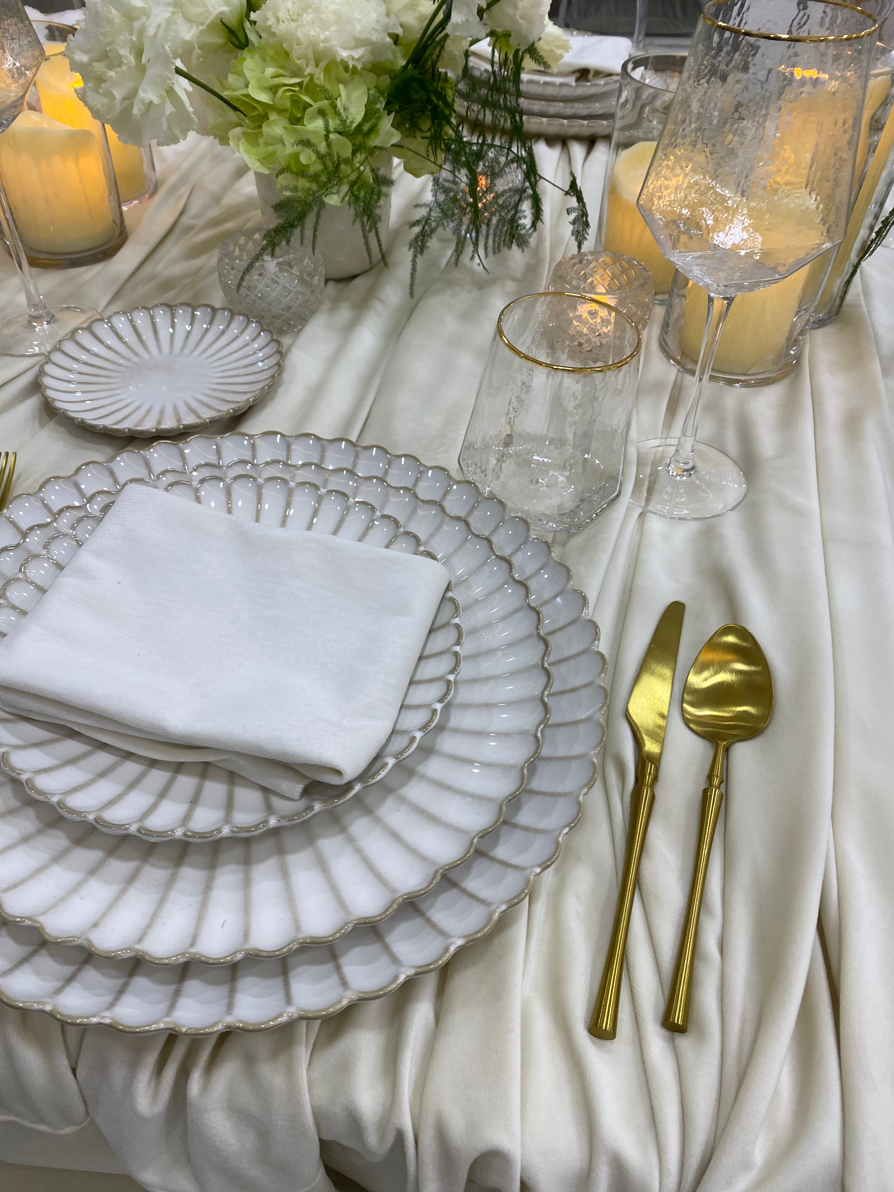 Classic Cream-Dining Setup featuring elegant white and gold tableware with scalloped edges, gold flatware, and floral centerpiece, perfect for formal gatherings or special occasions.