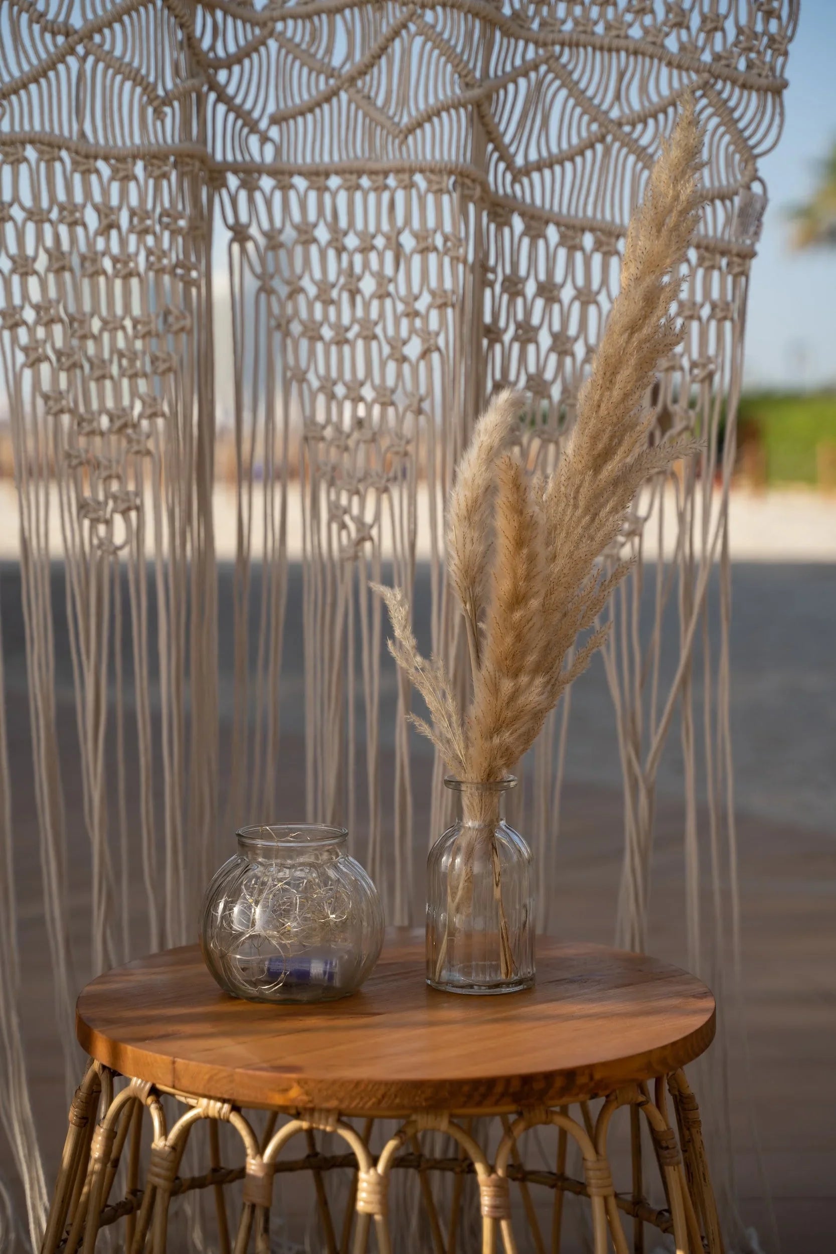 Mini clear vases on a table, showcasing various shapes ideal for home or event decor, with dried flowers and a glass jar nearby.