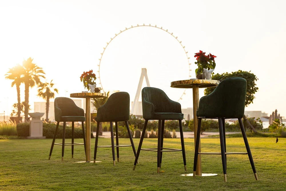 Gold cocktail tables on grass with a Ferris wheel in the background, ideal for versatile event setups.