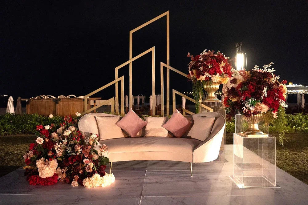 KOSHA SAND VELVET SOFA with wooden tapered legs, adorned with pillows and surrounded by floral decor, perfect for stylish lounge seating.