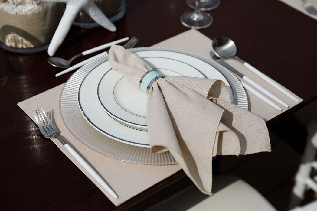 NAPKIN RING - SILVER & AQUA ROUND on a set table with a napkin and silverware, showcasing its elegant design suitable for any event setting.