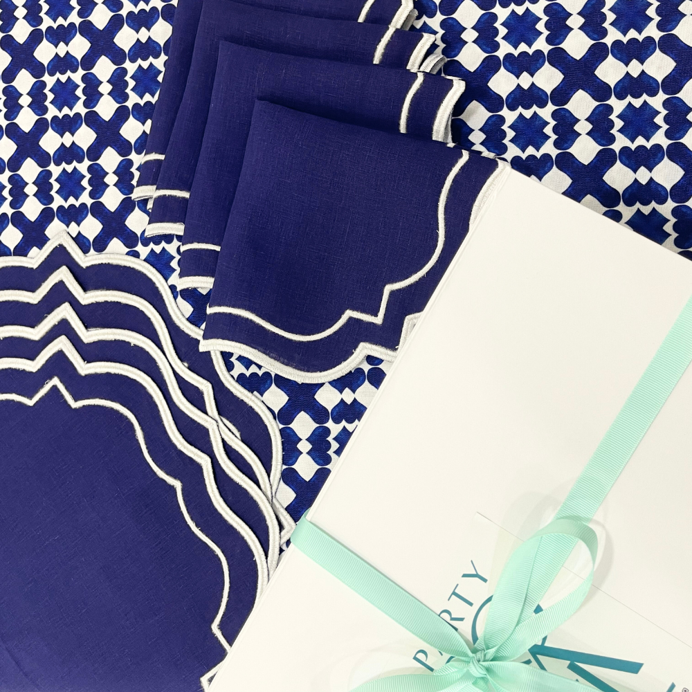 The Iftar Table Edit Gift Box featuring navy napkins, a patterned tablecloth, and a white gift box with aqua ribbon, perfect for Ramadan celebrations.