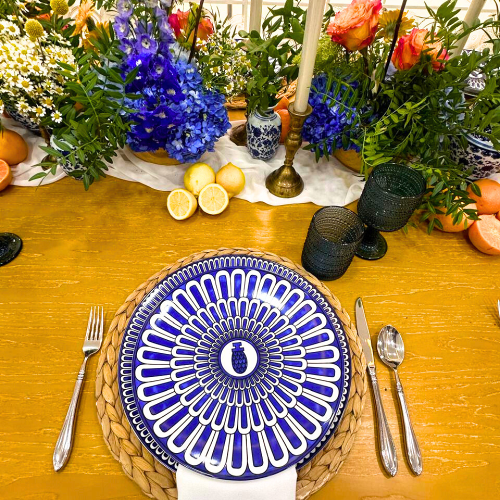 Overhead view of a table setting featuring the GEOMETRIC BLUE PLATES with a bold pattern, complemented by elegant tableware and vibrant floral centerpiece.