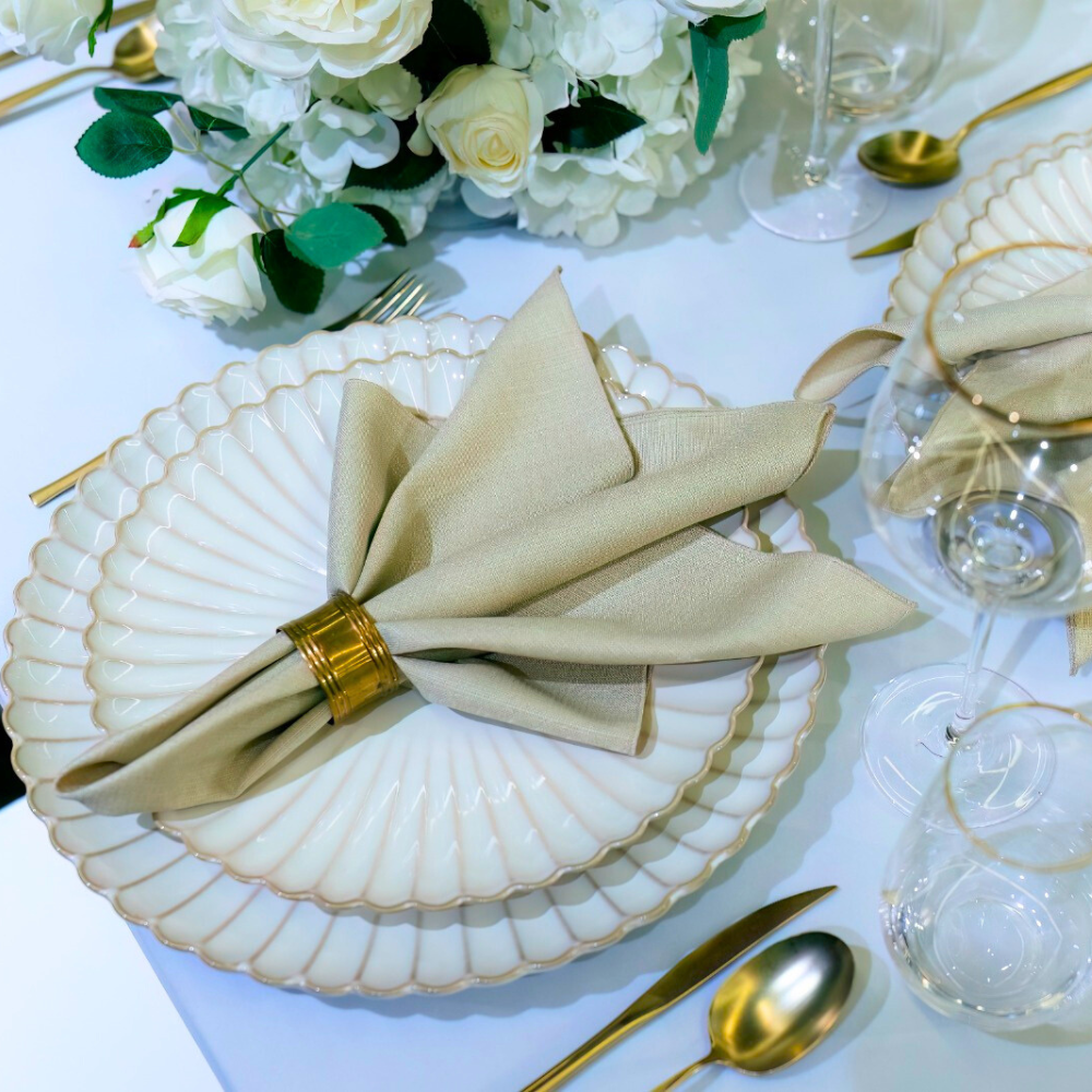 SCALLOPED LIKE PLATES elegantly displayed with gold flatware and a beige napkin, perfect for sophisticated dining events, featuring a unique shell-like design.