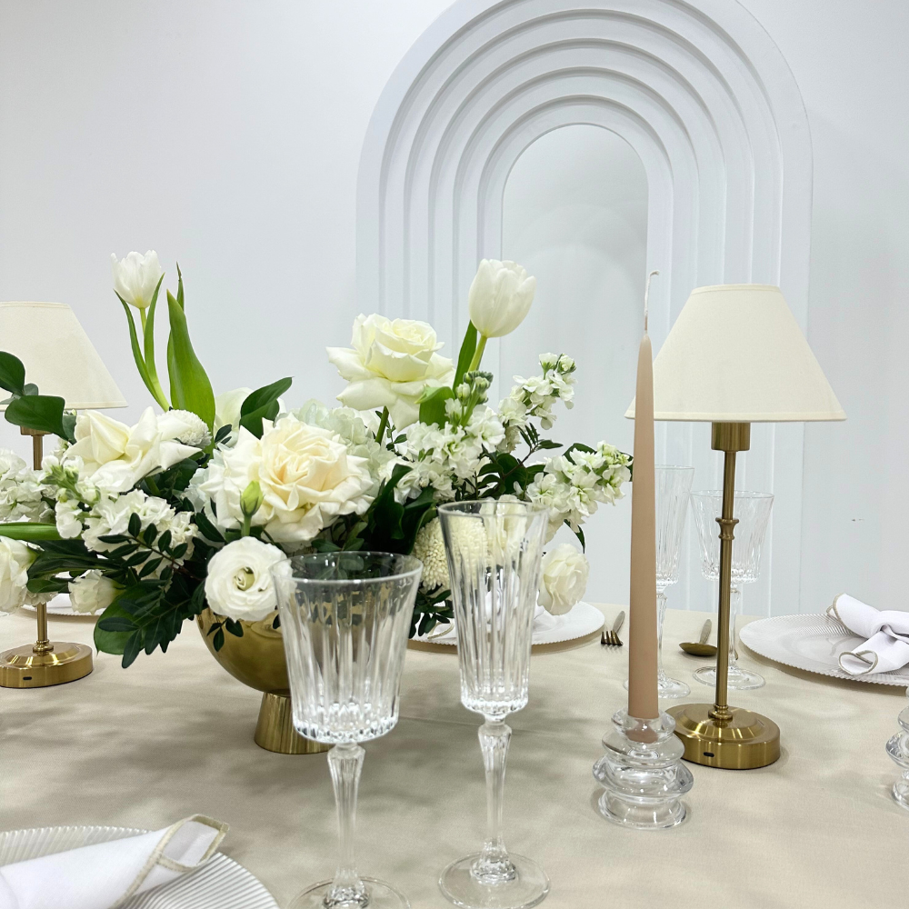 Off White with Gold Base Wireless Lamp on a table, surrounded by elegant white flowers and glasses, ideal for enhancing party or event ambiance.