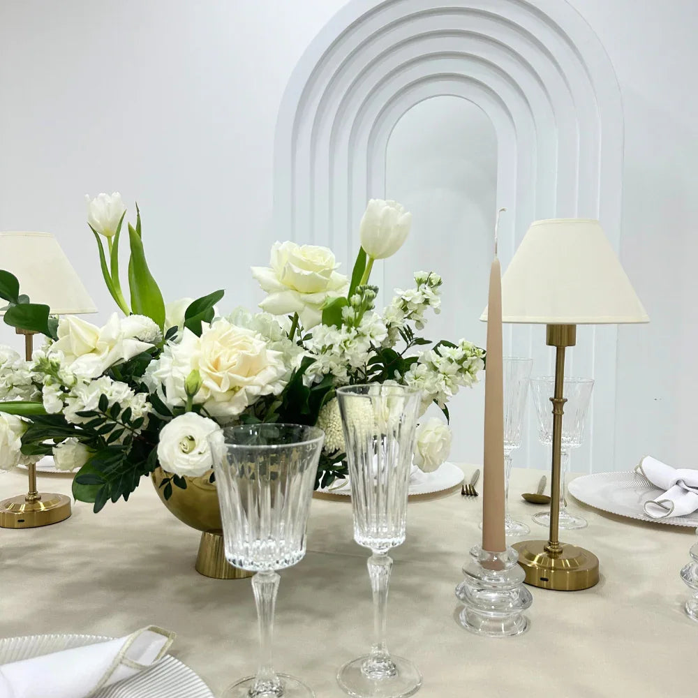 Off White with Gold Base Wireless Lamp on a table, surrounded by elegant white flowers and glasses, ideal for enhancing party or event ambiance.