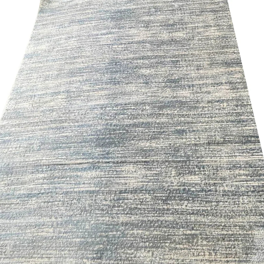 RUG GREY LOOMED: Close-up of a textured, low-pile rug with horizontal striations, offering understated elegance suitable for diverse décor styles, ideal for enhancing rental spaces.