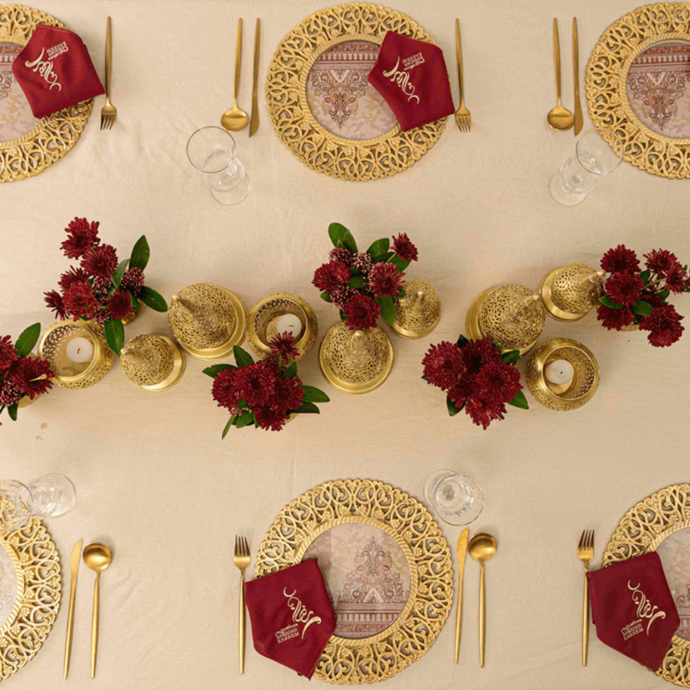 Vintage Arabesque - Dining Setup featuring a table for eight with gold plates, silverware, juice glasses, flower centerpieces, and ghost chairs, ideal for elegant events.
