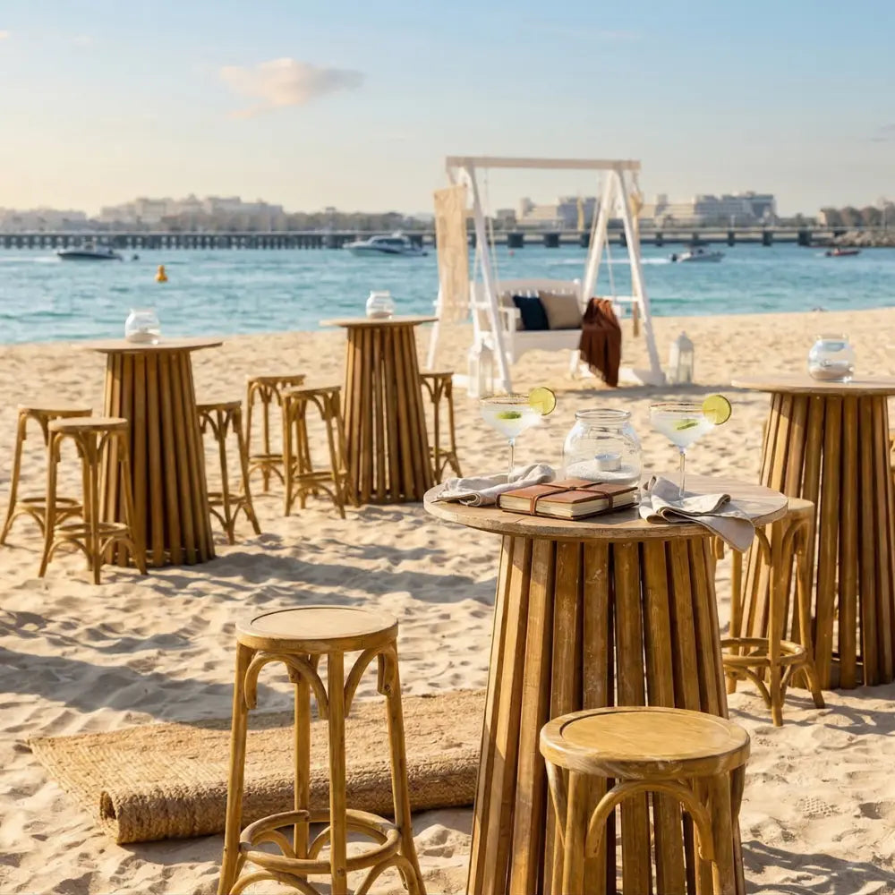 Wooden cocktail table set in a beach lounge with high stools, margarita cocktails, embodying a relaxed, tropical vibe for party or event settings.